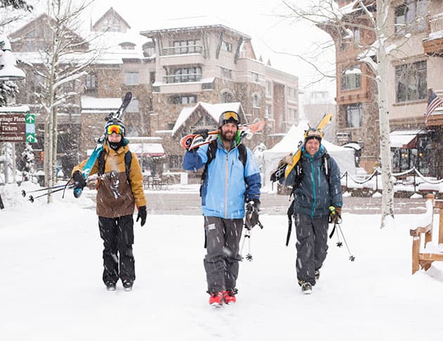 guys walking in the snow with their skiis